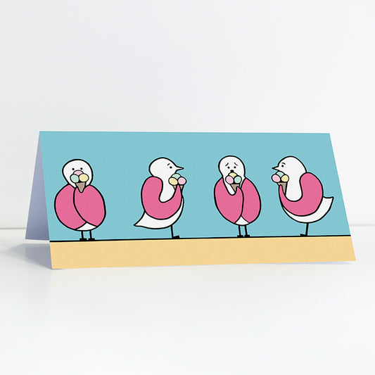Gift card with four pink winged seagulls holding an icecream cone on a sandy beach with a blue sky. Original artworks