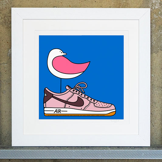Giclee original artwork print in a white mounted frame. A pink winged seagull is perched on top of a pale pink trainer that says air on the bottom. The seagull is looking back. The background is a bright blue.