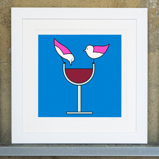Giclee original artwork print in a white mounted frame. A glass of red wine has two pink winged seagulls perched on the edge of the glass facing each other, one seagull is leaning down to look at the red wine. The background is bright blue, the glass is a pale green. All the details and shapes are outlined in black.