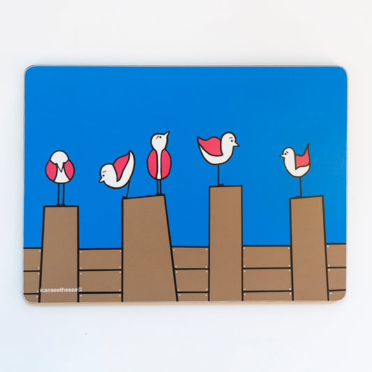 placemat from an original painting five pink wing seagulls are perched on four brown groynes with a bright blue background