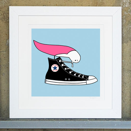 Giclee original artwork print in a white mounted frame. A pink winged seagull is perched on top of a black converse shoe pulling at a shoelace. The background is a pale blue and the original print is called I love my converse. The print is signed with Lizzie written in pencil in the bottom right corner. 