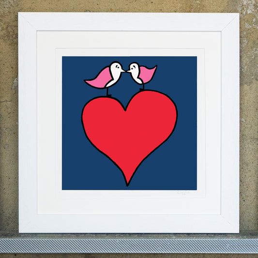 Giclee original artwork print in a white mounted frame. Two pink winged seagulls facing each other with beaks touching are on top a bright red heart. The background is a navy colour, all the details and shapes are outlined in thick black. The print is called my big heart.