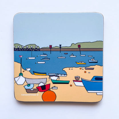 A coaster of a painting of emsworth boats. There is a beach with different coloured boats and orange buoys. The sea is blue with more boats in yellow, blue, red and white. The horizon has green with concreate wall, the sky is pale blue. On one of the boats on the beach, a pink winged seagull is perched ontop of the sail pole looking out. All the shapes and details are outlined in black liner. There are lots of colours, mainly blue.