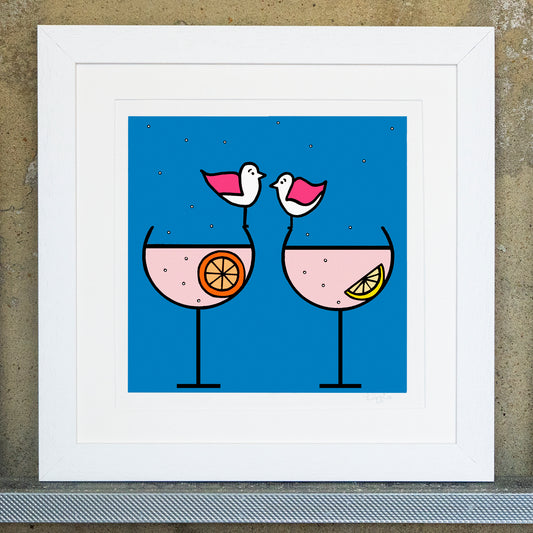 Giclee original artwork print in a white mounted frame. Two glasses of gin fizz are placed side by side one with a slice of lemon and the other a slice of orange. Bubbles are floating in the drink all the way up and out the glass. Two pink winged seagulls are perched on the edge of the glasses facing each other. The background is a bright blue, the gin fizz is a pale pink. All shapes and details are outlined in black.
