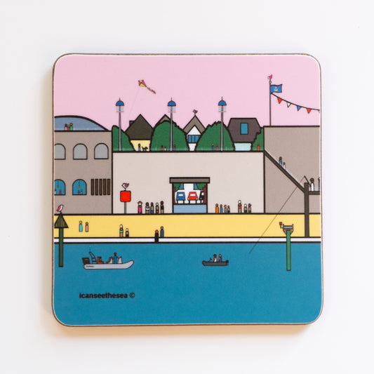 A coaster of a painting of Hotwalls in Old Portsmouth. The beach, steps and view points have lots of figures in different colours. Behind the wall you can see trees and the tops of buildings, the sky is pale pink and the blue sea has small fishing boats. A kite flys in the sky, a figure is fishing and there are pink winged seagulls on tops of the buildings.