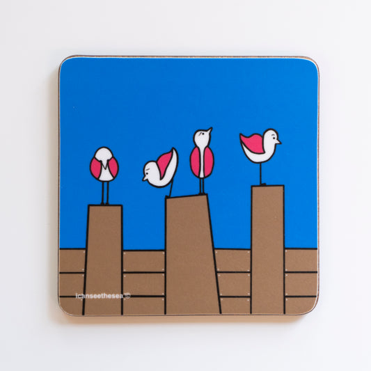coaster from an original painting four pink wing seagulls are perched on three brown groynes with a bright blue background with icanseethesea text on the bottom left