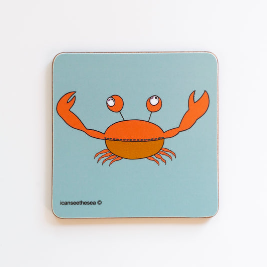 Pastel blue sage coloured coaster of a painting of an orange crab. The crabs eyes have pink winged seagulls flying in the reflection of its pupils. Facing forward the crab is lifting both its pincers.