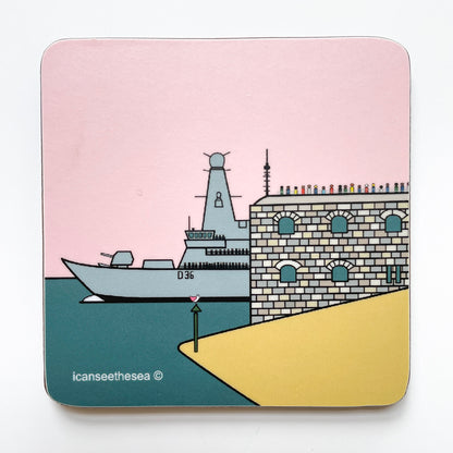 A coaster of a painting of the historic round tower and HMS Defender D36. The sky is pastel pink, the sea teal and the sand yellow. The round tower has figures standing in the viewpoint at the top in different coloured outfits looking out. The HMS Defender is coming out from behind the round tower with the navy stood on the balconies, the ship is pale grey. On the beach is a green sea marker, and a small pink winged seagull is sitting on top.