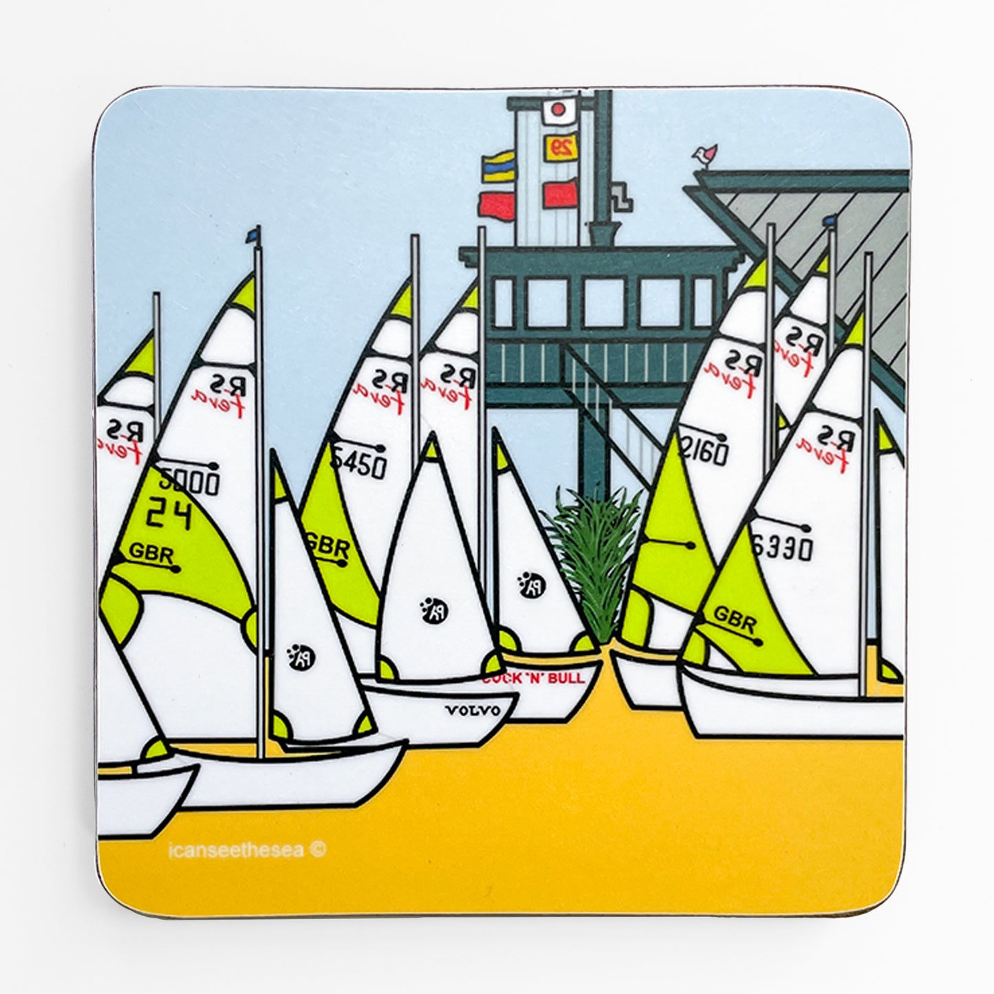 A coaster of sailing boats. The sand is bright yellow with sailing boats parked on the beach with lime green and white with numbers and logos. Behind them is a wooden lookout with steps, balcony and mast with flags. On top of the lookout sits a pink winged seagull. The sky is pastel blue and some green plants are growing round the bottom of the lookout under the steps.