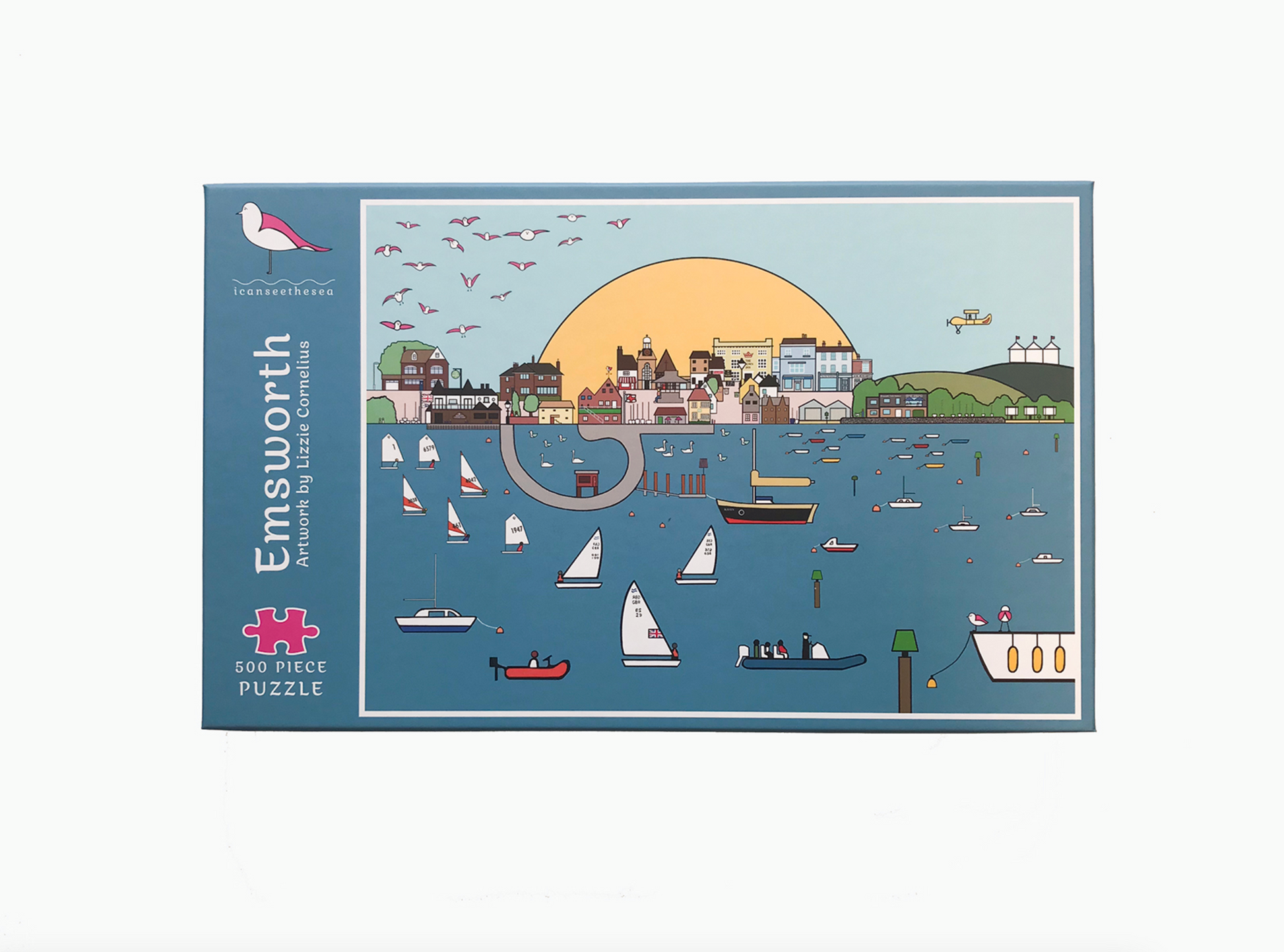 The front of a jigsaw package is displayed on a white background. The jigsaw package says emsworth artwork by Lizzie Cornelius and 500 piece puzzle. On the right is a painting of emsworth with boats, swans, pink winged seagulls, a landscape with different houses and buildings and a big yellow sun and blue sky in the background. The colours are mainly blues with some yellow, greens and browns. 