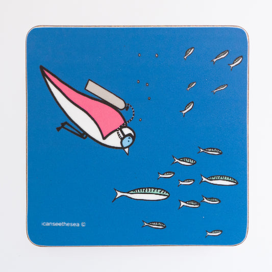 A coaster of a painting of a seagull swimming. The background is bright blue with small white and pale green fish swimming in a group. Behind them is a pink winged seagull with a scuba diving tank and goggles with a few bubbles.