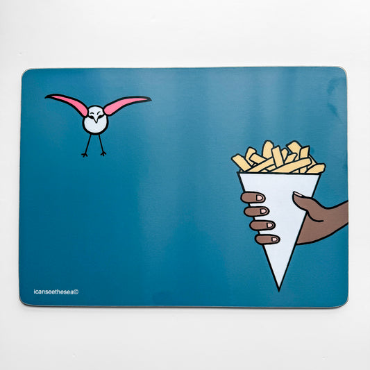 A teal coloured placemat of a painting of chips and seagull. A hand holds out a white cone filled with beige coloured chips. Above the hand to the left is a pink winged seagull flying towards the chips with its wings and legs outstretched.